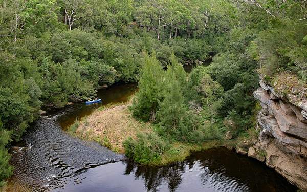 A kayaker on the Kangaroo River below sandstone banks, seen from Hampden Bridge